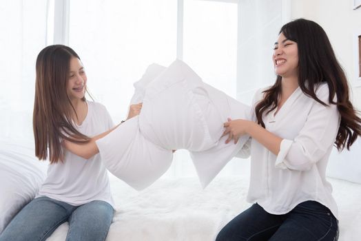 Two Asian girls doing pillow fight in bedroom as childhood. Lifestyles and People concept. Relation and friendship theme. Couple and friends concept. LGBT and people lifestyle