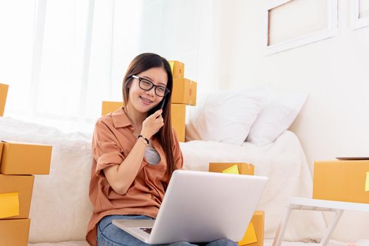 Beauty Asian woman using laptop and calling phone on bed. Business and Technology concept. Delivery and Online shopping concept. Post and Service theme. People lifestyle remote work in domestic house