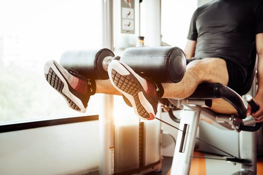 Close up of man lifting weight by two legs for stretching muscle at fitness gym at private condominium background. Sport and People lifestyles concept.