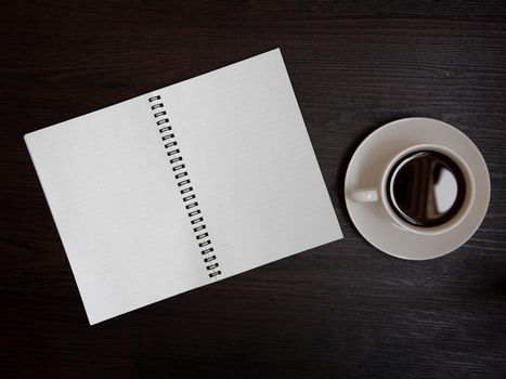 Top view of coffee cup and blank notebook for memo on wooden background. Business and object concept. Memo and reminder theme.