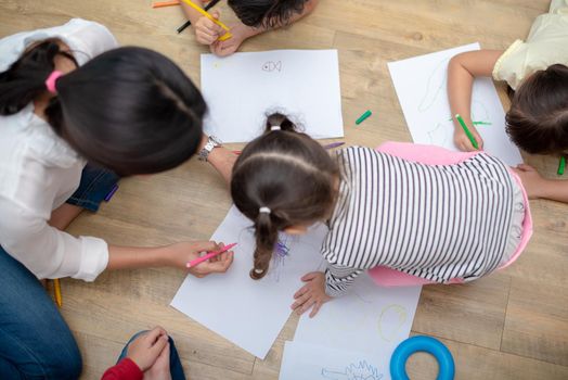Group of preschool student and teacher drawing on paper in art class. Back to school and Education concept. People and lifestyles theme.  Room in nursery