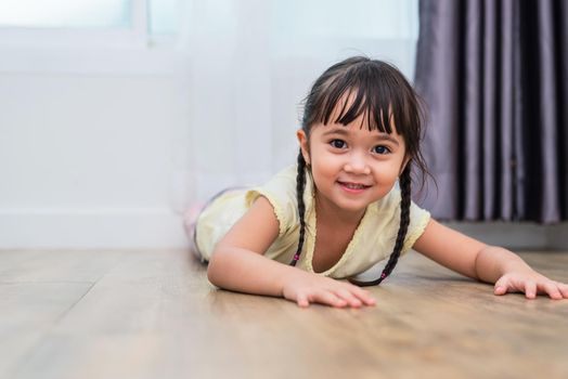 Portrait of cute little girl lying on floor with barefoot and looking at camera at home. People lifestyles concept.