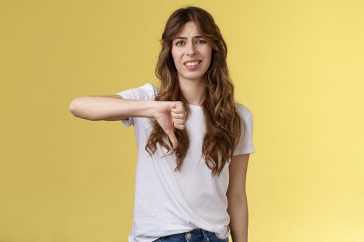 So lame you loser. Ignorant snobbish good-looking woman give own judgement negative opinion disagree grimacing cringe dislike show thumb down disappointed unimpressed yellow background