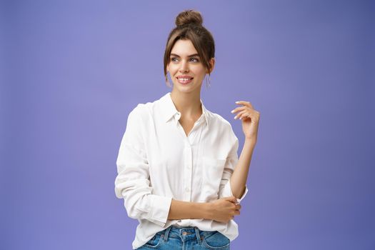 Feminine and stylish modern charming girl with gapped teeth and pimple posing in trendy white blouse and round earrings gazing left charmed and sensual with cute smile over purple background