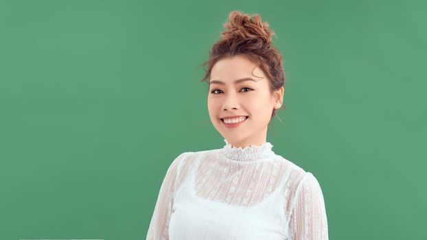 Young friendly Asian woman with smiley face isolated on green background.