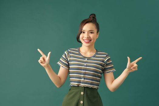Portrait of a smiling girl pointing with index fingers in opposite sides, smiling timidly, having difficulty to make a choice