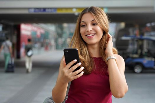 Charming beautiful business woman smile holds smartphone walking in train or metro station