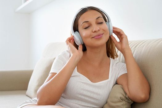 Brazilian teenager relaxing and listening to music with wireless headphones at home