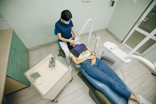 Dentist doing teeth whitening procedure with ultraviolet lamp. Concept of teeth care and dentistry. Led teeth whitening. Ultraviolet rays. Lamp for teeth enamel whitening.