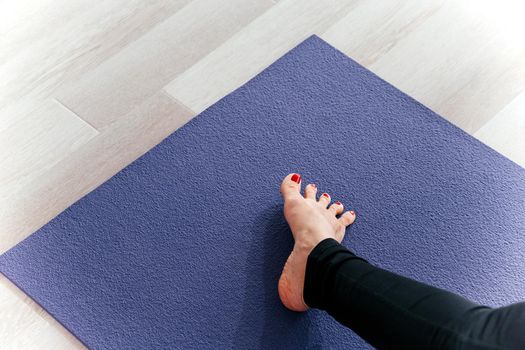 Yoga woman stretching feet spreading her toes doing toe stretch on exercise mat