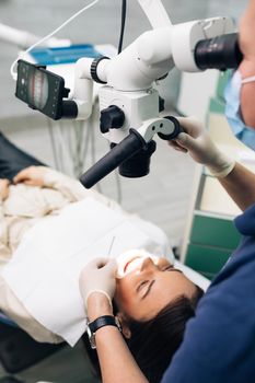 Close-up of a dentist using microscope. Modern equipment microscope in dental office. Doctor dentist using dental microscope in modern dental office. The endodontist is treating canals.