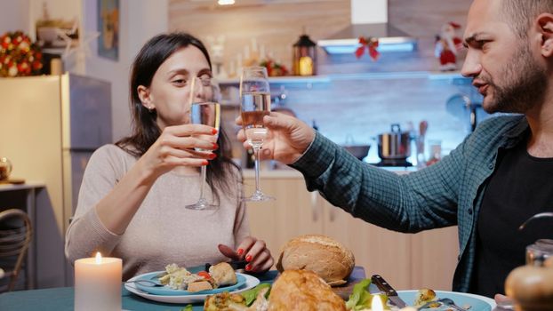Man and woman eating chicken and clinking glasses with champagne