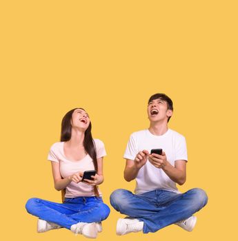 Excited young couple using mobile phone and looking above