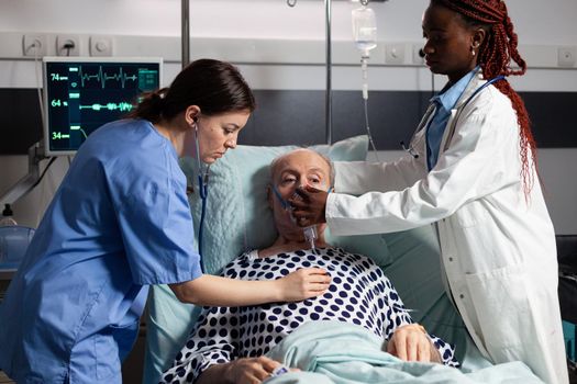 African doctor and medical assistant helping senior man breath