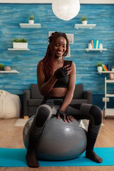 Sporty athletic black woman relaxing on stability ball