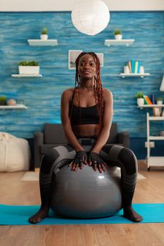 Sportive strong black woman sitting on stability ball