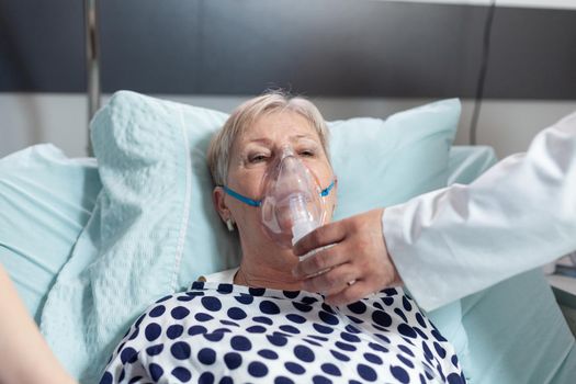 Doctor and nurse supervising senior woman breathing with oxygen mask