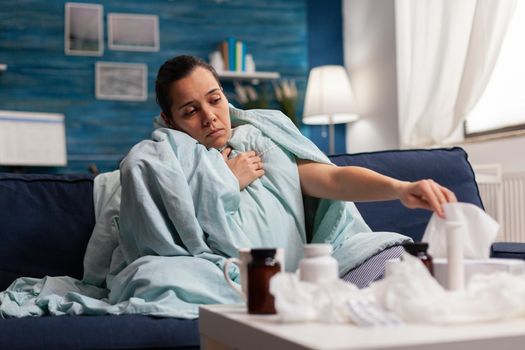 Sick woman wrapped in blanket at home with virus infection
