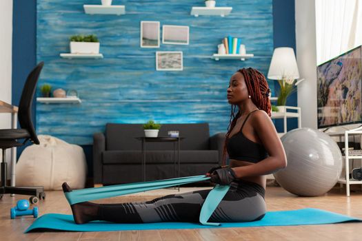 Black woman doing pilates workout using elastic strap