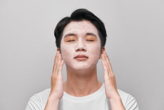 Handsome man with clay mask on his face against white background