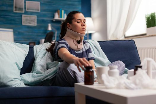Woman in neck brace suffering from pain on sofa
