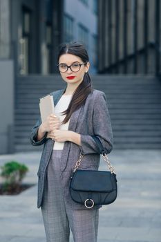 Attractive young businesswoman with specs wear grey elegant suit. Portrait of young businesswoman wearing glasses with a serious face.