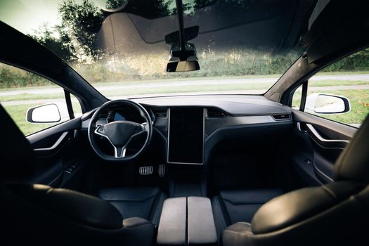Electric car interior details of door handle with windows controls and adjustments. Inside car interior with front seats, driver and passenger textile windows door panels console