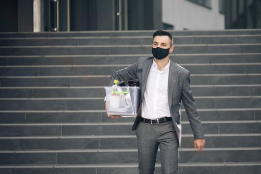 Fired man walking outdoor. Depressed jobless person. Unemployment concept. Left without money. Sad male office worker in depression with box of personal stuff. Businessman lost job