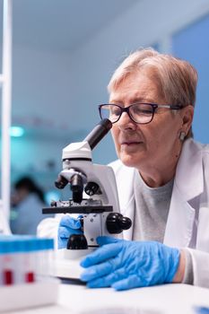 Senior scientist chemist analysing reaction of virus on microscope in laboratory