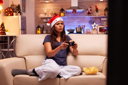 Woman lying on couch playing online videogame using gaming joystick