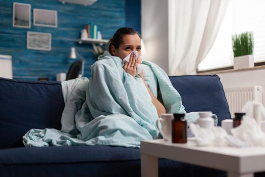 Woman with sickness wrapped in blanket at home ill