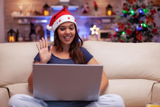 Smiling woman greeting remote friends enjoying christmastime together