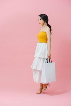 Cute glamour young asian lady posing with white bags of purchases