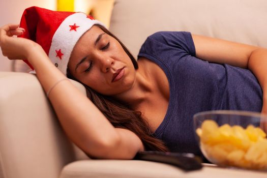 Adult person with santa hat sleeping on sofa after watching december entertainment movie