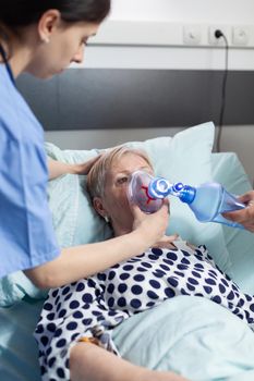 Doctor and nurse helping sick hospitalized senior woman breath