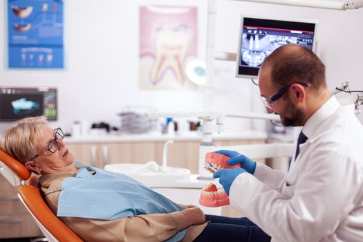 Dentist holding model of oral cavity with teeth