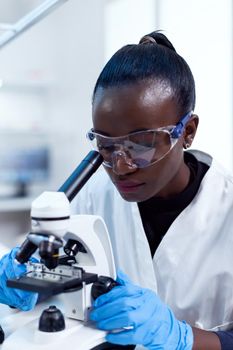 Biochemistry technician with african ethnicity using microscope