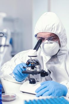 Medical engineer adjusting microscope wearing ppe