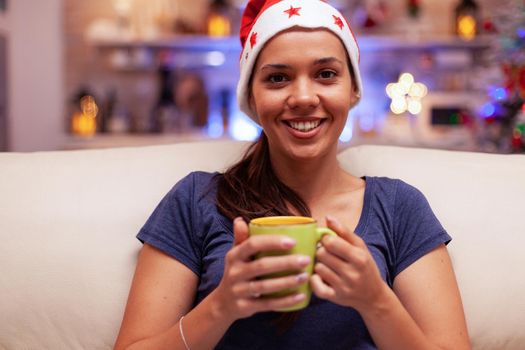 Portrait of smiling woman holding cup of coffee in hands during christmastime
