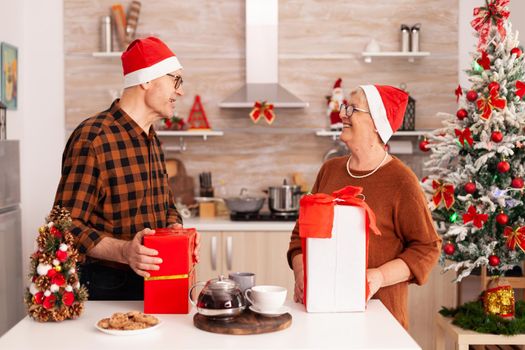 Grandparents surprising each other with xmas wrapper gift enjoying christmas holiday