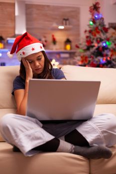 Tired exhausted woman falling asleep on couch in xmas decorated kitchen
