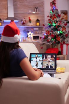Woman lying on sofa talking with remote friends celebrating christmastime