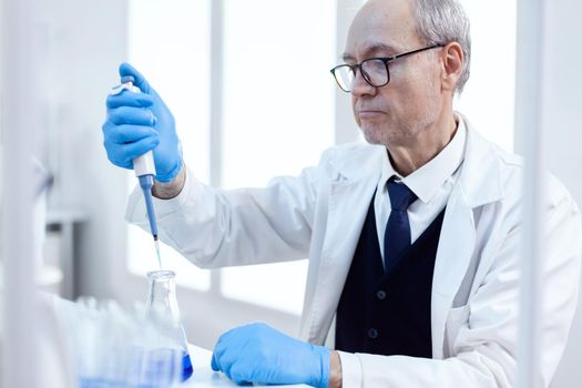 Elderly scientist doing pharmaceutical experiment