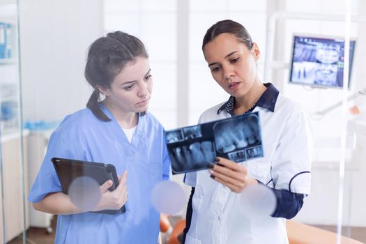 Orthodontist and nurse in stomatology office holding teeth x-ray