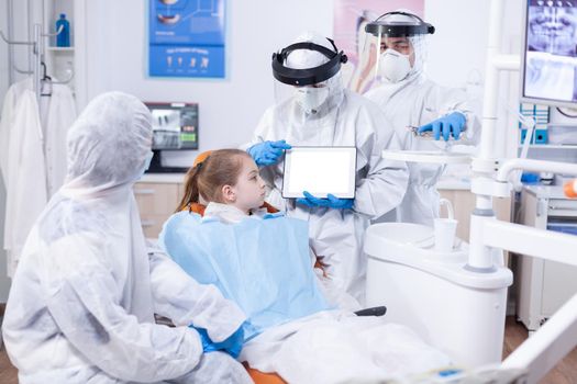 Dentist dressed in ppe suit using digital device