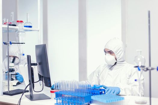 Microbiologist dressed in sterile ppe suit researching for covid vaccine