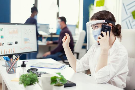 Business administrator sitting at her workplace wearing face mask during covid 19