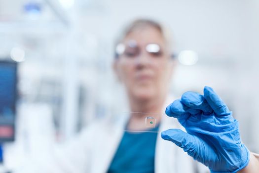 Close up of senior scientist holding biochemistry material on glass slide