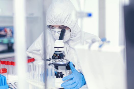 Scientist in sterile protection suit analysing coronavirus