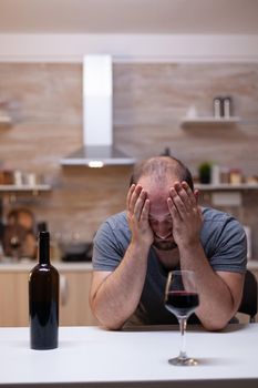 Desperate man feeling miserable while having glass with wine